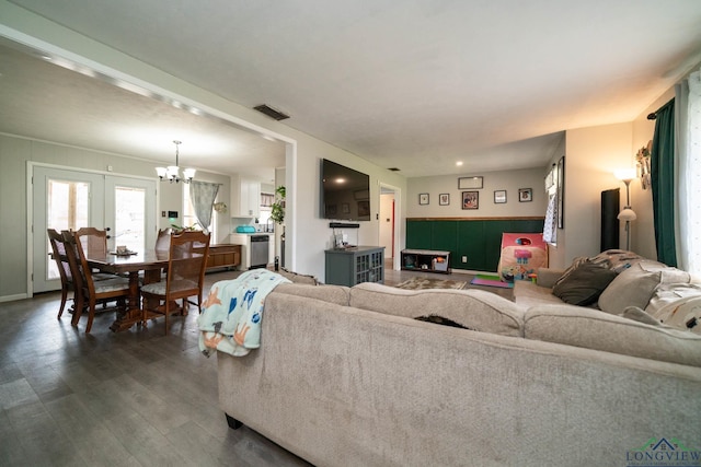 living area with dark wood-type flooring, visible vents, and a chandelier