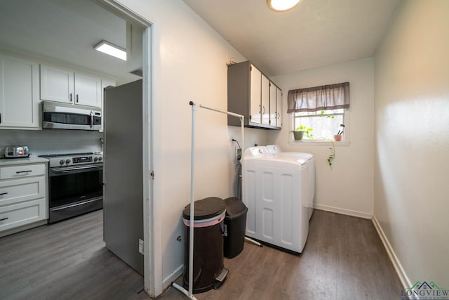 laundry area with dark wood finished floors, laundry area, baseboards, and washer and clothes dryer