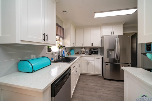 kitchen with decorative backsplash, white cabinets, appliances with stainless steel finishes, and a sink