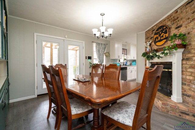 dining room with a notable chandelier, dark wood-type flooring, brick wall, and ornamental molding