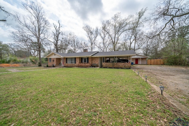 single story home with fence, dirt driveway, a front yard, a chimney, and a carport