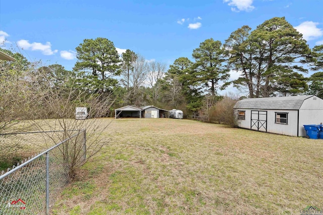 view of yard featuring a carport, fence, an outdoor structure, and a storage shed