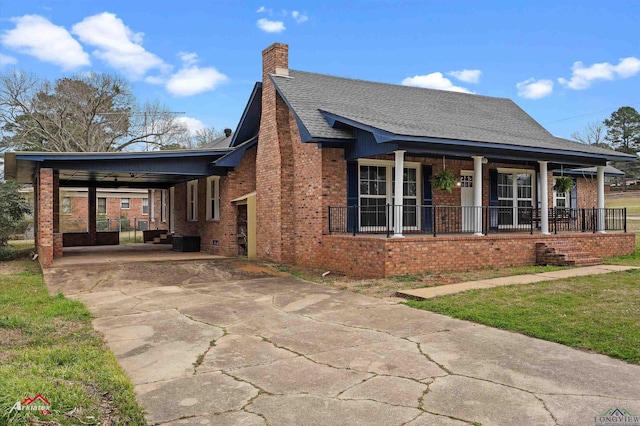 view of front facade with concrete driveway, a chimney, roof with shingles, covered porch, and brick siding