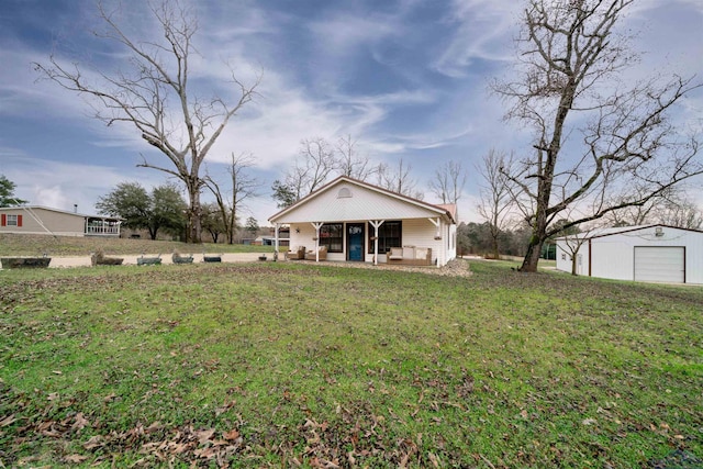 rear view of property with a garage, a yard, and a porch