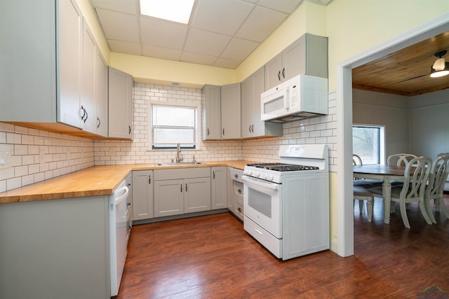 kitchen featuring wood counters, sink, tasteful backsplash, dark hardwood / wood-style floors, and white appliances