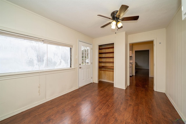 unfurnished room with ceiling fan, a textured ceiling, built in features, and dark hardwood / wood-style flooring