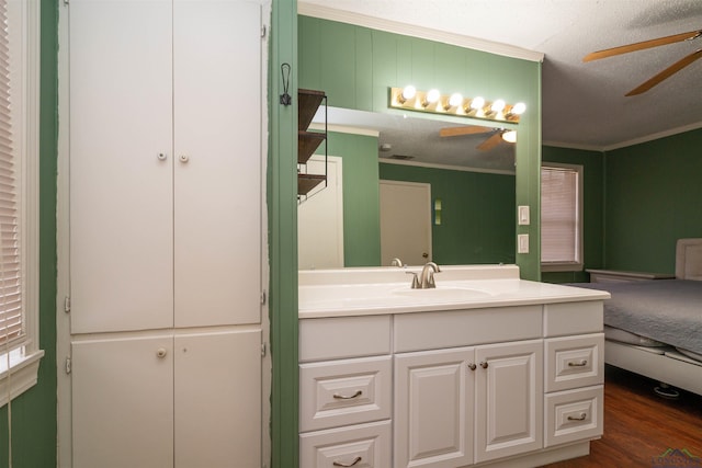 bathroom with crown molding, ceiling fan, wood-type flooring, and vanity