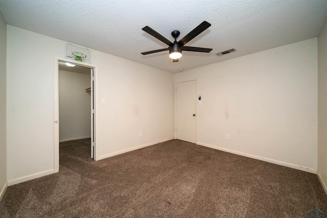 unfurnished room featuring ceiling fan, a textured ceiling, and dark carpet