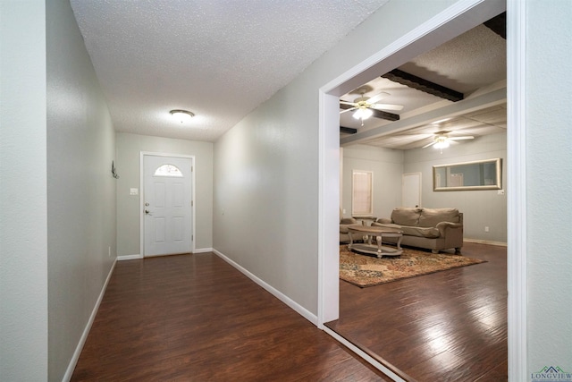 foyer entrance with beamed ceiling, ceiling fan, dark hardwood / wood-style floors, and a textured ceiling