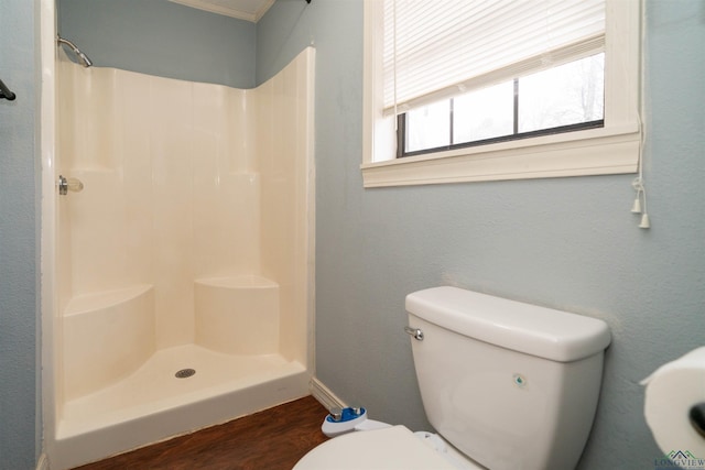 bathroom featuring a shower, hardwood / wood-style floors, and toilet