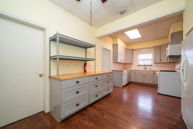 kitchen featuring butcher block countertops, white appliances, dark wood-type flooring, sink, and gray cabinetry