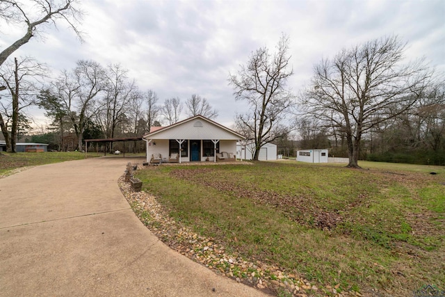 ranch-style house featuring a front yard, covered porch, and a storage shed