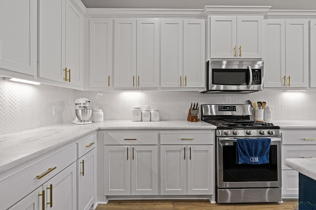 kitchen featuring stainless steel appliances, white cabinetry, and tasteful backsplash