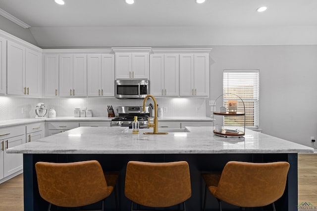 kitchen featuring sink, white cabinets, a center island with sink, and stainless steel appliances