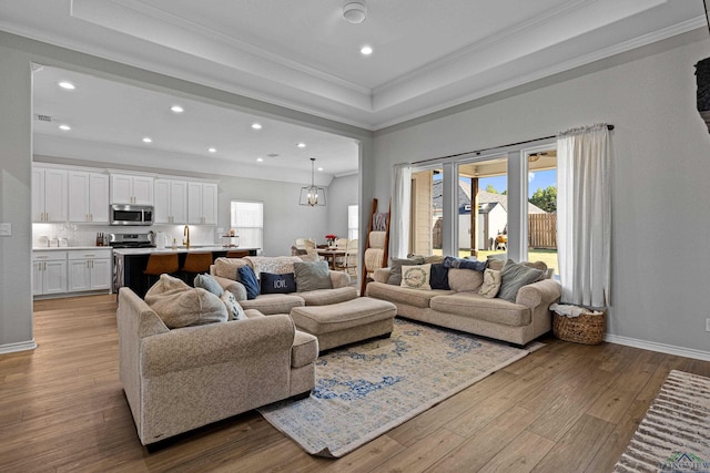 living room with crown molding, light wood-type flooring, and a healthy amount of sunlight