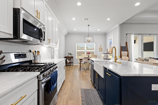 kitchen featuring appliances with stainless steel finishes, white cabinets, ornamental molding, pendant lighting, and backsplash