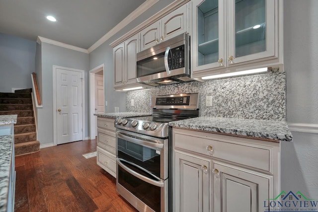 kitchen featuring ornamental molding, stainless steel appliances, light stone countertops, and decorative backsplash