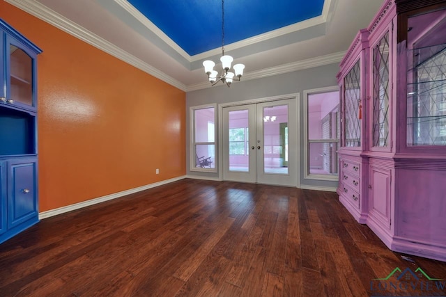 unfurnished dining area with dark hardwood / wood-style flooring, a tray ceiling, crown molding, an inviting chandelier, and french doors