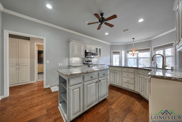 kitchen with sink, stainless steel appliances, dark hardwood / wood-style floors, a kitchen island, and decorative light fixtures