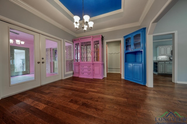 unfurnished dining area featuring french doors, crown molding, a chandelier, dark hardwood / wood-style floors, and a tray ceiling