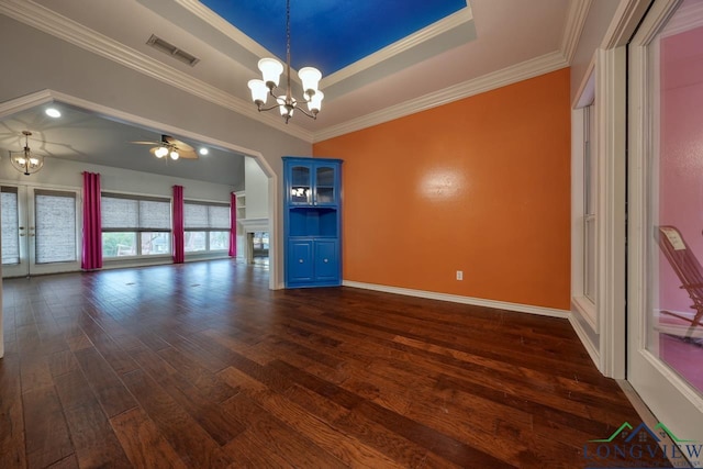 unfurnished room featuring ceiling fan with notable chandelier, dark wood-type flooring, ornamental molding, and a raised ceiling