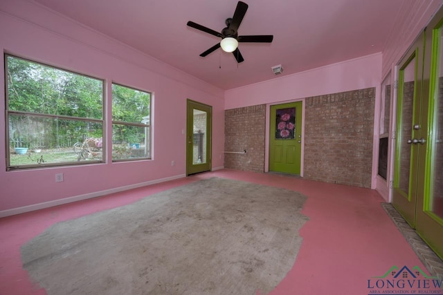 carpeted spare room featuring crown molding, ceiling fan, and brick wall