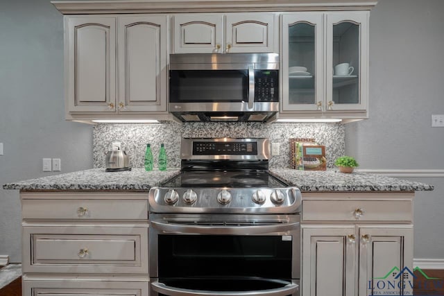 519 Hideaway Ln E, Hideaway, TX 75771 - kitchen with glass insert cabinets, backsplash, light stone counters, and appliances with stainless steel finishes
