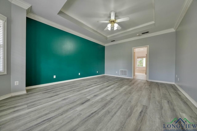 unfurnished room with crown molding, a tray ceiling, light hardwood / wood-style flooring, and ceiling fan