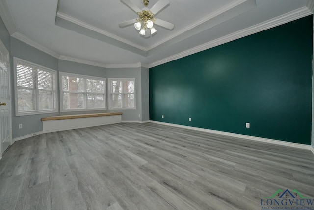 unfurnished room with plenty of natural light, light hardwood / wood-style flooring, ceiling fan, and a tray ceiling