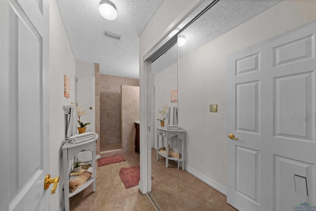 bathroom featuring a textured ceiling, tile patterned floors, and walk in shower