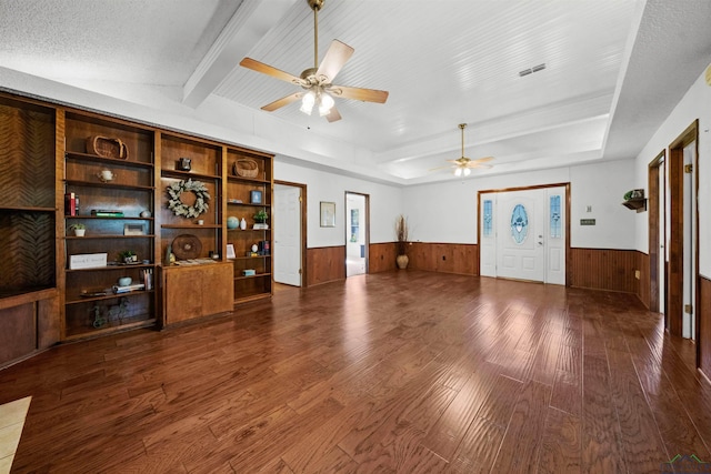 unfurnished living room with beamed ceiling, hardwood / wood-style floors, a textured ceiling, and ceiling fan