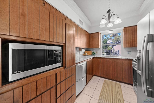 kitchen with appliances with stainless steel finishes, a textured ceiling, sink, light tile patterned floors, and a notable chandelier