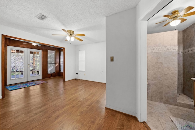 spare room with light wood-type flooring, a textured ceiling, and french doors