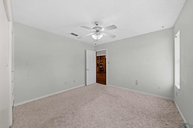 carpeted empty room featuring ceiling fan and a textured ceiling