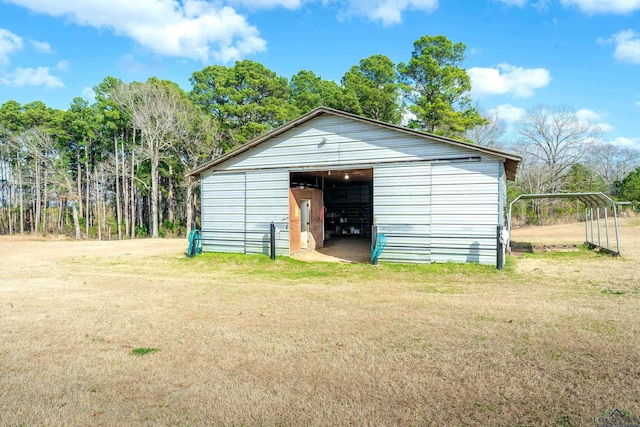 view of outdoor structure with a carport and a yard