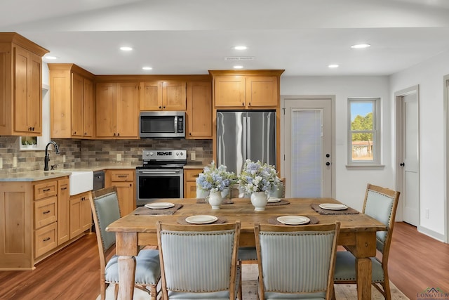 kitchen featuring sink, decorative backsplash, stainless steel appliances, and hardwood / wood-style floors