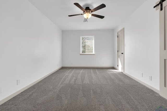 carpeted spare room featuring ceiling fan and a barn door