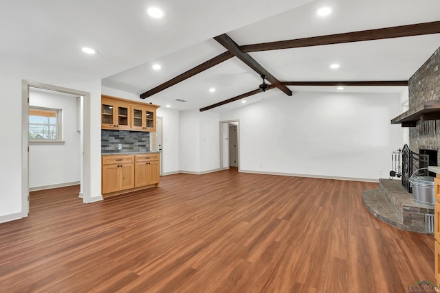 unfurnished living room with hardwood / wood-style flooring, ceiling fan, a fireplace, and lofted ceiling with beams