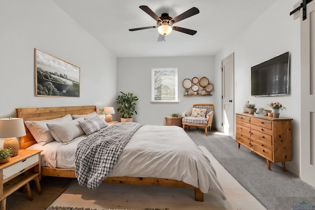 bedroom featuring a barn door and ceiling fan