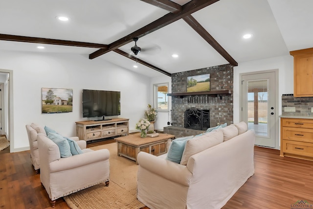 living room featuring plenty of natural light, hardwood / wood-style floors, a brick fireplace, and vaulted ceiling with beams