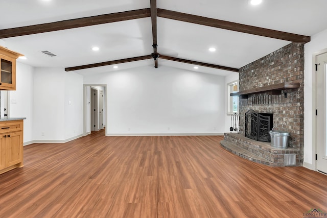 unfurnished living room with wood-type flooring, a fireplace, and lofted ceiling with beams