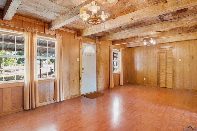 foyer entrance featuring beamed ceiling, an inviting chandelier, wood ceiling, and wood walls