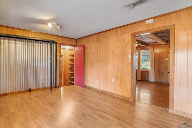 unfurnished room with wood walls, hardwood / wood-style floors, and a textured ceiling