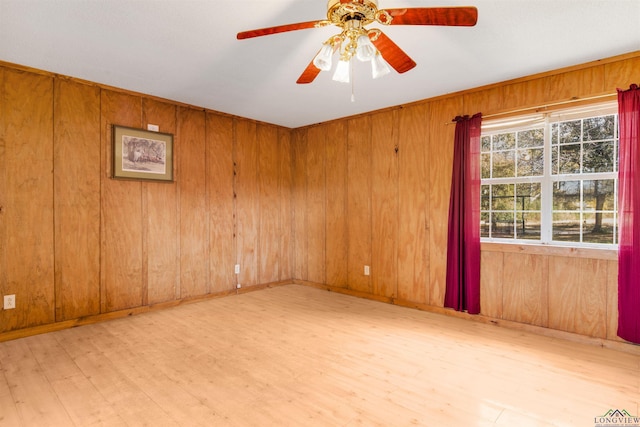 spare room featuring light hardwood / wood-style flooring, ceiling fan, and wood walls