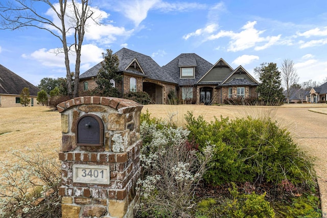 view of front facade with brick siding and a front lawn