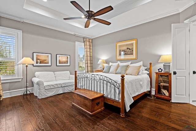 bedroom featuring hardwood / wood-style floors, baseboards, a tray ceiling, and crown molding