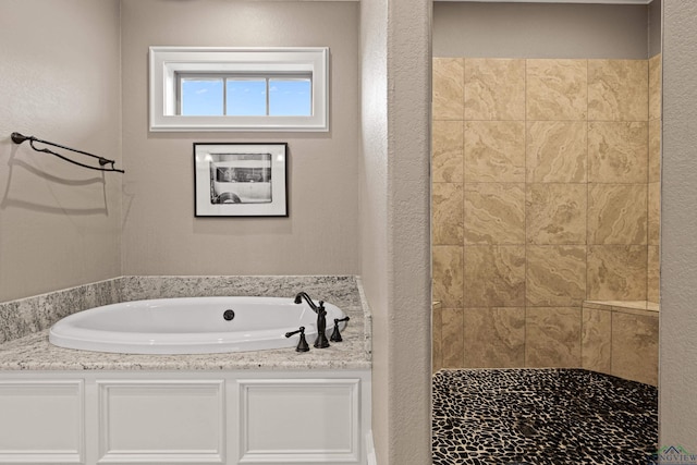 full bath with a garden tub, a textured wall, and tiled shower