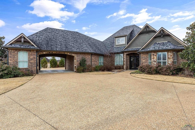 craftsman-style home featuring a shingled roof, concrete driveway, and brick siding