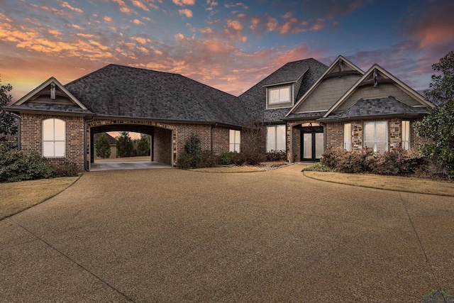 view of front facade featuring brick siding, driveway, and roof with shingles