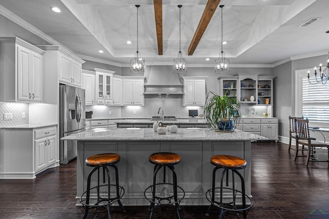 kitchen with white cabinets, stainless steel fridge with ice dispenser, dark wood-type flooring, premium range hood, and a kitchen bar